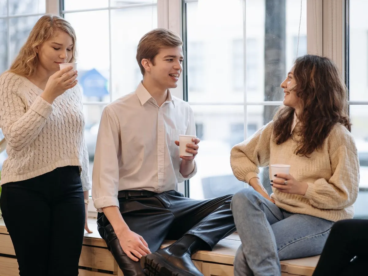Three friends chatting over coffee by a window