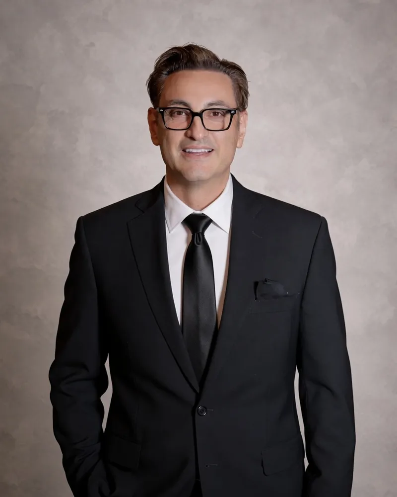 Pedro Lira in a suit and glasses, studio portrait