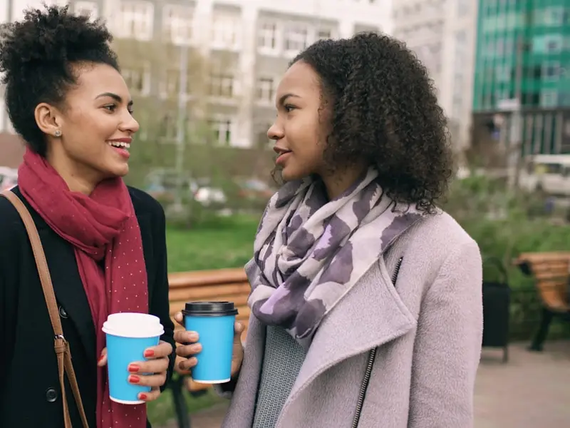 Two women talking over coffee, outdoors