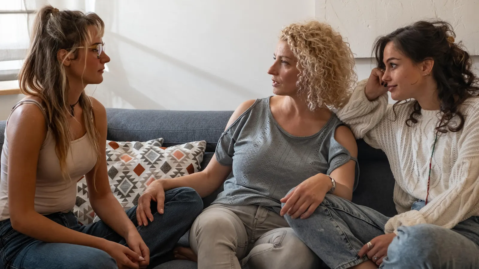 Tres mujeres conversando sentadas en un sofá